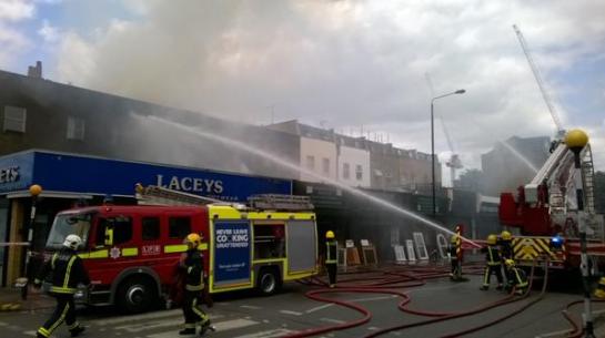 Crews working hard fighting the fire on Yorkton St in Hackney range of shops and roof alight (Image: London Fire Brigade)